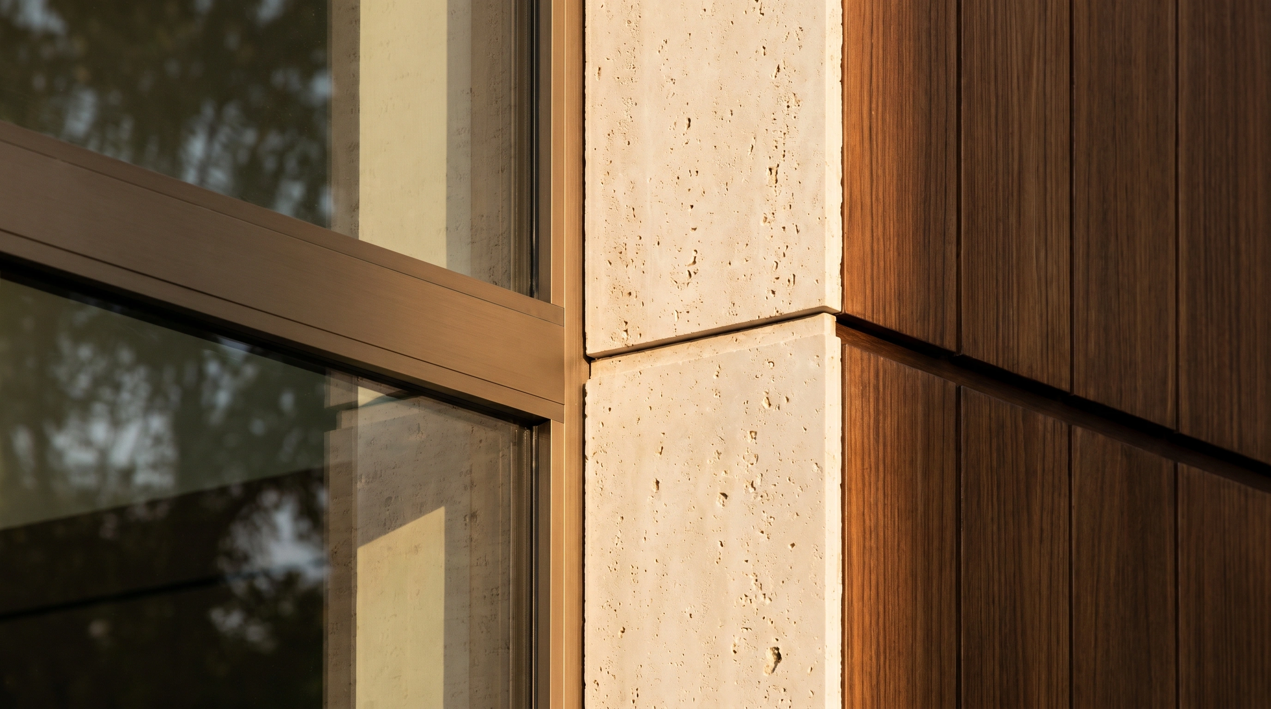 Travertine limestone meeting teak slat cladding and bronze window frame